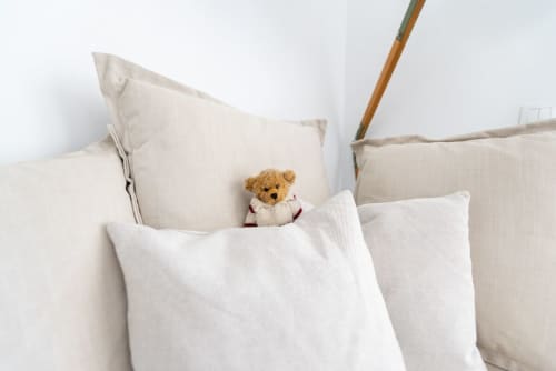 Acogedora cama en Smart Rent Fuerteventura con almohadas mullidas y osito de peluche, reflejando el confort del apartamento Fuerte Hygge