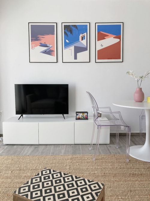 Salón moderno en apartamento de Fuerteventura con TV, sillas transparentes, mesa redonda blanca y decoración temática costera