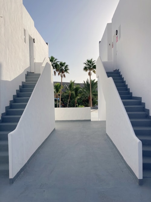 Moderna escalera blanca de arquitectura contemporánea en Smart Rent Fuerteventura con palmeras visibles a través de la abertura central