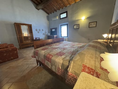 Spaziosa camera da letto all'Agriturismo Aggazzotti con letto in legno, armadio e arredi rustici a Colombaro
