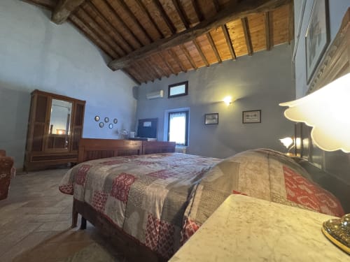 Spaziosa camera da letto presso l'Agriturismo Aggazzotti con due letti, soffitto in travi di legno e servizi moderni a Colombaro, Italia