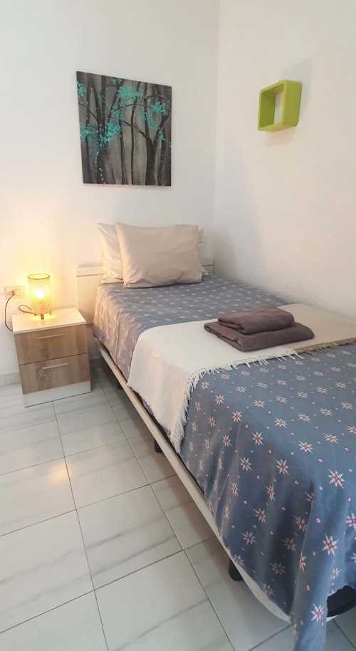 Cozy bedroom at Alquila en Canarias, El Médano with twin beds, turquoise artwork, and beige bedding near the beach