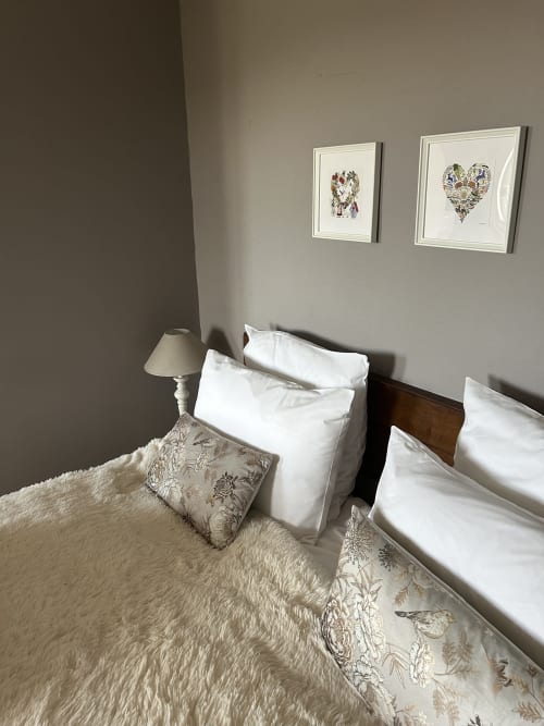 Bedroom at Le Clos d'Azel B&B in Alsace with white pillows, patterned bedding, framed heart artwork, and bedside lamp