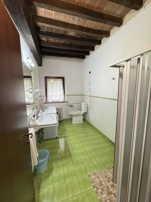 Spacious bathroom in Agriturismo Aggazzotti with green tile floors, dual sinks, toilet, and shower in Colombaro, Formigine