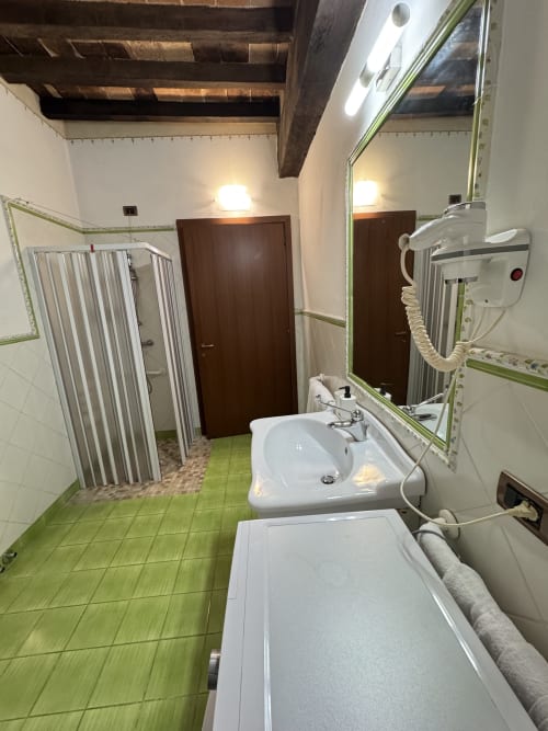 Bathroom at Agriturismo Aggazzotti with green tiled floor, white sink, bathtub, and shower enclosure in Colombaro, Italy