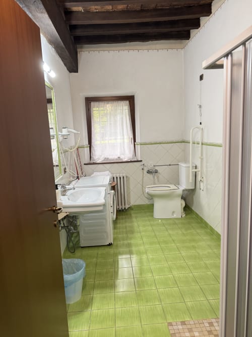 Bathroom at Agriturismo Aggazzotti with green tile floor, white sink, toilet, and shower enclosure