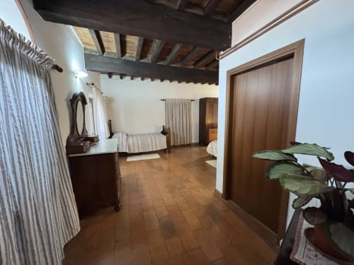 Spacious bedroom at Agriturismo Aggazzotti B&B in Colombaro with exposed beams, terracotta floors, and wooden doors