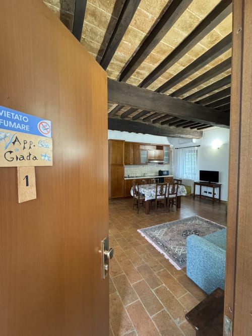 Ingresso dell'appartamento Giada all'Agriturismo Aggazzotti: soggiorno con travi in legno, tavolo da pranzo e cucina a vista