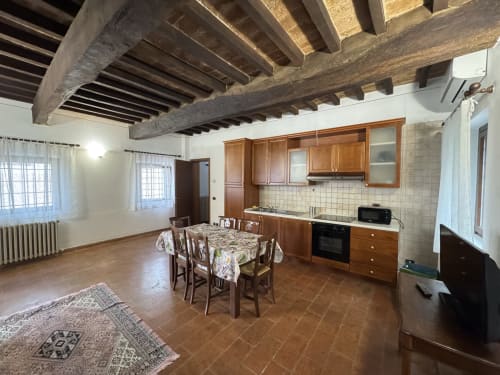 Agriturismo Aggazzotti apartment in Colombaro with exposed beams, wooden kitchen, dining table, and rustic terracotta