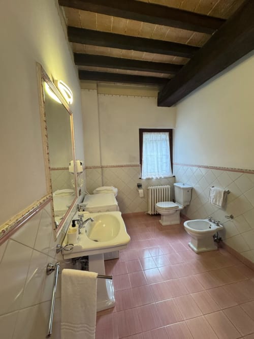 Spacious bathroom at Agriturismo Aggazzotti in Colombaro with dual sinks, bidet, toilet, and exposed beam ceiling
