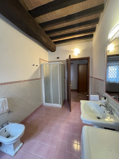 Spacious bathroom at Agriturismo Aggazzotti with double sinks, toilet, shower, wooden beams