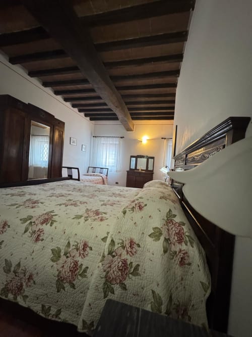 Agata room at Agriturismo Aggazzotti with floral bedspread, wooden beams, and traditional Italian countryside decor