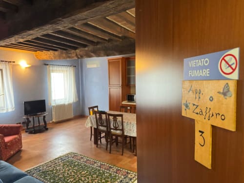 Appartamento Zaffiro all'Agriturismo Aggazzotti di Colombaro: soggiorno con travi in legno e cartello vietato fumare