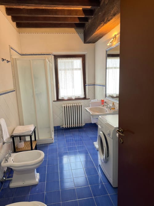 Spacious bathroom at Agriturismo Aggazzotti with blue tile floor, shower, toilet, sink, and washing machine