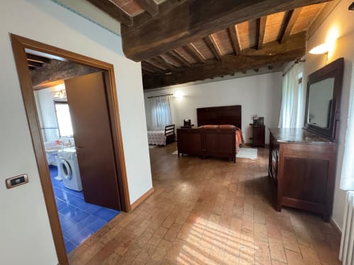 Spacious bedroom suite at Agriturismo Aggazzotti with wooden beams, terracotta floors, dark wood furniture and en-suite