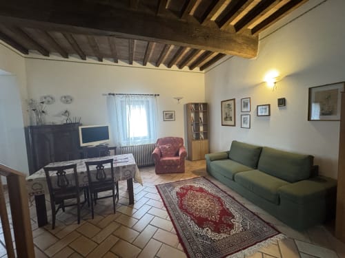 Cozy living room at Agriturismo Aggazzotti with green sofa, exposed wooden beams, and traditional furnishings in Colombaro