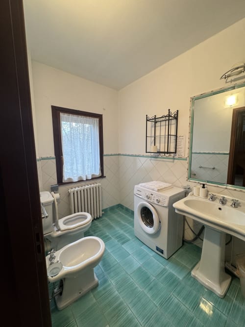 Spacious bathroom in Appartamento Acquamarina at Agriturismo Aggazzotti, featuring dual sinks, washing machine, and green