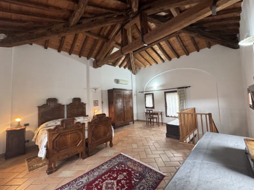 Spacious bedroom at Agriturismo Aggazzotti with wooden beams, terracotta floors, and antique furniture