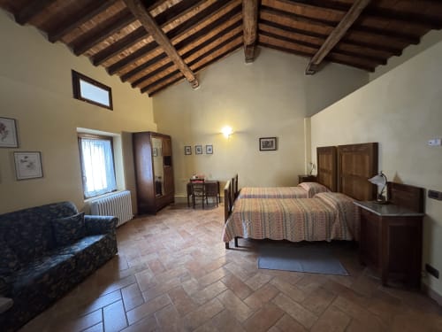 Camera spaziosa all'Agriturismo Aggazzotti a Colombaro con travi in legno, pavimenti in cotto e stile rustico tradizionale