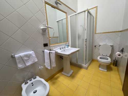 Bagno della Camera 7 presso l'Agriturismo Aggazzotti, Colombaro, Italia con pavimento giallo, lavabo su colonna e box doccia