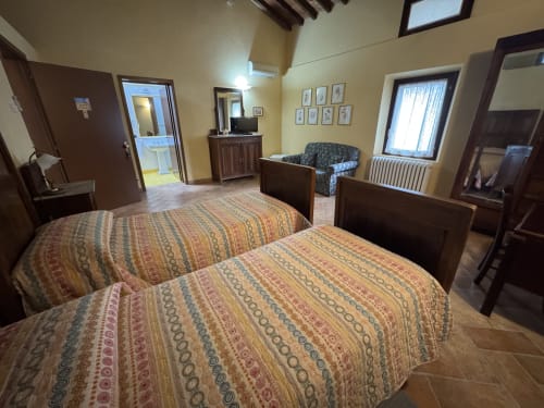 Ampia camera da letto presso Agriturismo Aggazzotti con due letti, bagno en-suite e arredamento rustico