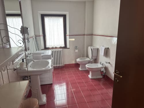 Spacious bathroom at Agriturismo Aggazzotti with red tile floor, dual sinks, bidet, and toilet in Colombaro, Italy