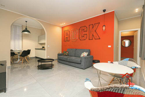 Moderno appartamento a Genova con caratteristica parete ROCK arancione, divano grigio e ampio living con zona pranzo