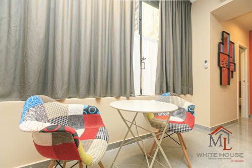 Zona pranzo di moderno appartamento con sedie patchwork colorate, tavolo rotondo e ampie finestre sulla piazza del Centro di Genova