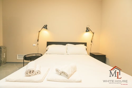 Camera da letto ML White House Genova Centro Storico con letto matrimoniale, biancheria bianca e lampade a parete regolabili