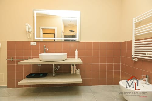 Bagno moderno nell'appartamento ML White House Genova con lavabo da appoggio, ripiani sospesi, piastrelle in terracotta e scaldasalviette