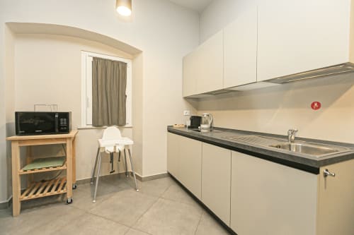 Cucina moderna in appartamento nel Centro Storico di Genova con arredamenti bianchi, lavello in acciaio inox e zona pranzo