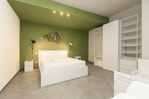 Camera da letto moderna nell'appartamento genovese con parete d'accento verde, arredi bianchi e vista sulla città