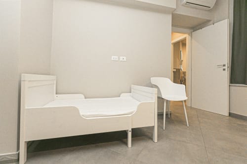 Appartamento ML White House nel Centro Storico di Genova con letto ospedaliero, sedia e vista sulla città