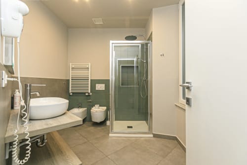 Bagno moderno negli Appartamenti Centro Storico di Genova con lavabo rotondo, doccia con piastrelle verdi e scaldasalviette