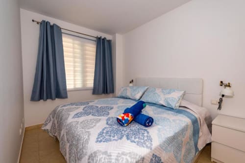 Dormitorio luminoso en apartamento Casa Laguna con ropa de cama azul estampada, cortinas azules y paredes blancas en Smart Rent