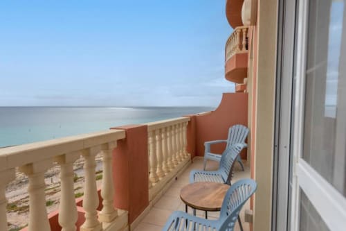 Balcón de Casa Laguna con sillas azules frente al océano turqueso, Fuerteventura