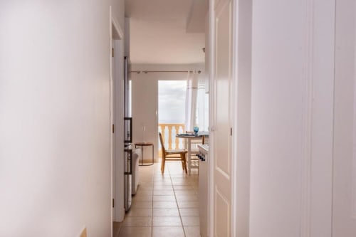 Pasillo luminoso con puertas blancas hacia la cocina y comedor del apartamento Casa Laguna con vista de balcón