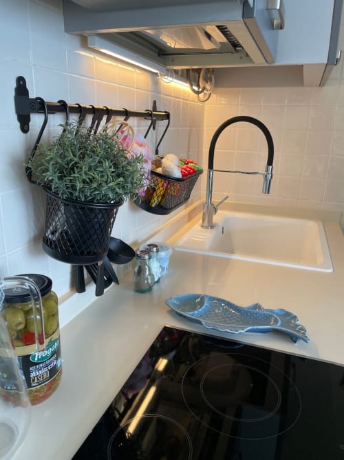 Cocina moderna con azulejos blancos tipo metro, estufa eléctrica negra, fregadero con grifo extraíble y macetas de hierbas colgantes en Smart