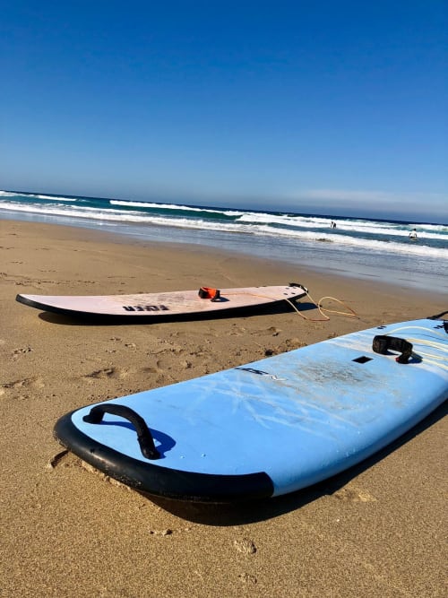 Tablas de surf en la playa de arena de Fuerteventura con olas del océano y cielo azul despejado