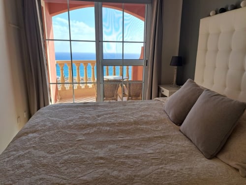 Dormitorio luminoso con balcón vista al mar, cabecero blanco, ropa de cama marrón y terraza frente al océano en Smart Rent Fuerteventura