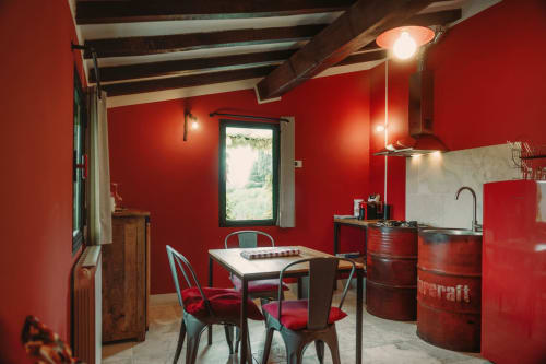 Cucina e zona pranzo con muri rossi ad Agriturismo Il Serraglio, Montepulciano, con travi a vista e comfort moderni