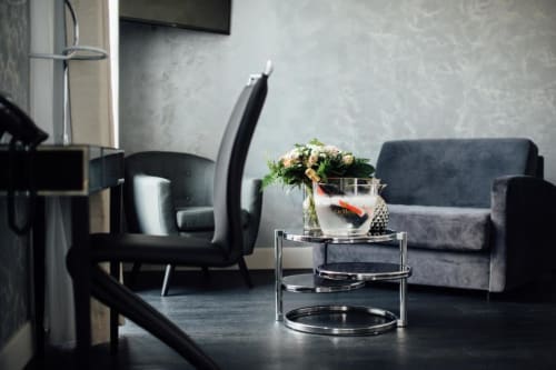 Espace de détente moderne à l'Hôtel Amirauté La Baule avec canapé gris, fauteuil noir et table en verre fleurie