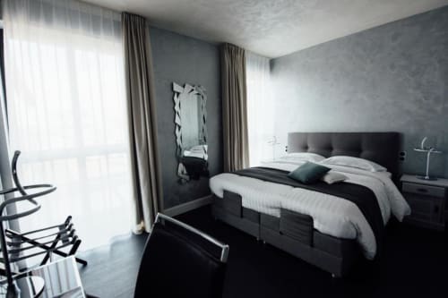 Modern double bedroom with spa bath at Hôtel Amirauté la Baule, featuring black bed, grey walls, city view, and contemporary