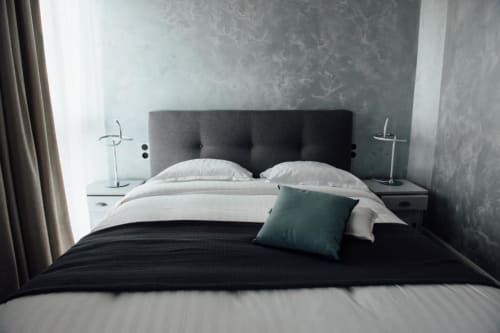 Modern double bed with dark headboard and white pillows in Hotel Amirauté La Baule room with city view
