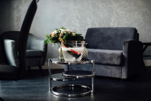 Élégant salon de l'Hôtel Amirauté avec fauteuils noirs, table d'appoint tiérée et composition florale