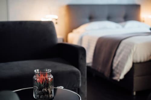 Modern hotel bedroom at Hôtel Amirauté la Baule with black armchair, flowers, and king bed with white linens