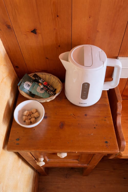 Bouilloire Philips blanche avec sachets de café et sucres sur table de nuit en bois à Chez Francine, Notre Dame de Bellecombe
