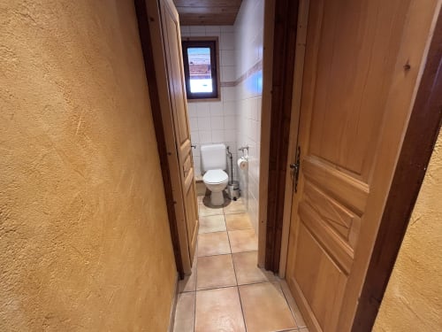 Étroit couloir avec portes en bois menant à la salle de bains avec toilettes de Chez Francine, Notre Dame de Bellecombe
