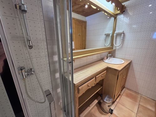 Salle de bain moderne chez Francine avec douche, meuble-lavabo en bois, miroir et murs carrelés à Notre Dame de Bellecombe