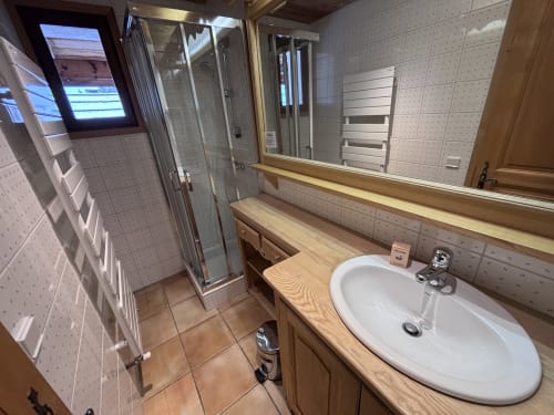 Salle de bains moderne avec lavabo blanc, meuble-vasque en bois, grand miroir et douche vitrée chez Chez Francine, Notre Dame de